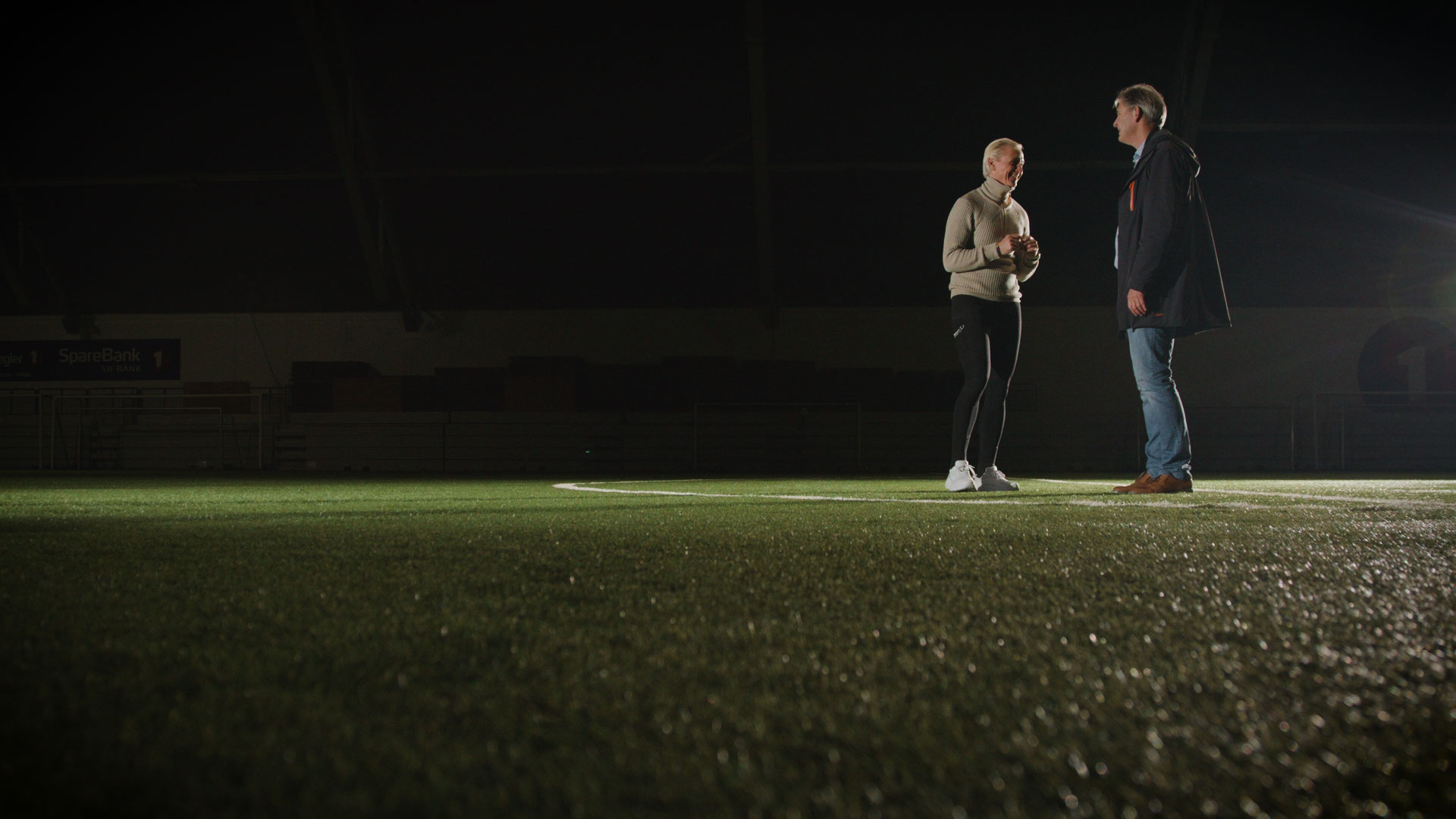 2 personer på en fotballbane, i mørket